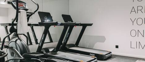 A gym with treadmills, a stationary bike, and a wall with motivational text.