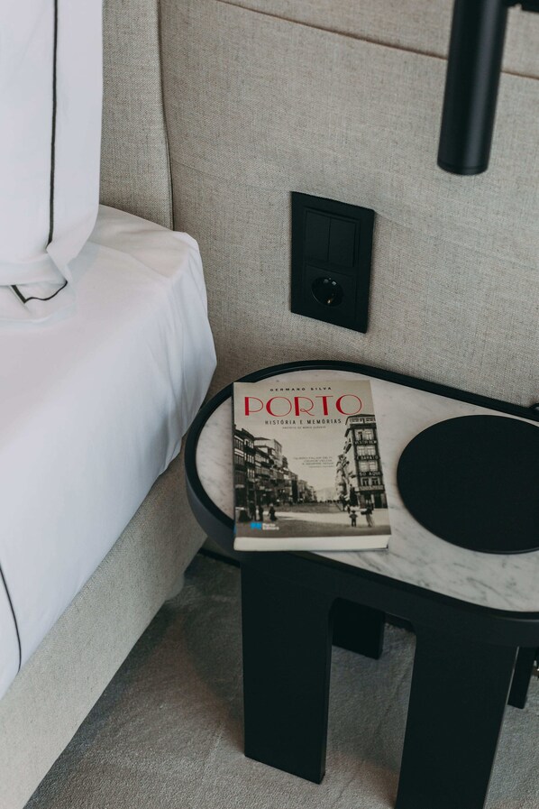 A neatly arranged room with a white sofa, a small black table with a magazine, and a black wall-mounted device.