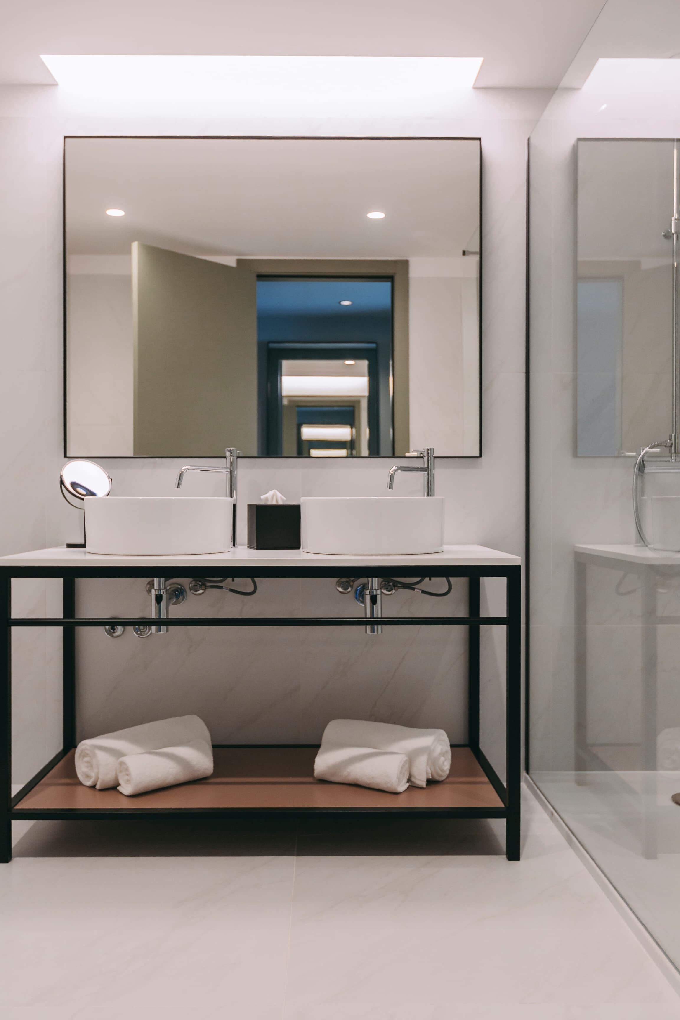 A modern bathroom with a double sink, a large mirror, and a glass shower enclosure.