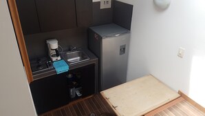 Eine kompakte Küche mit Gasherd, Kaffeemaschine, Spüle und einem kleinen Kühlschrank.