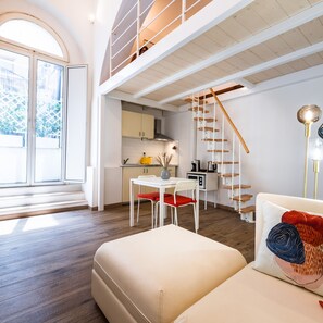 A modern loft apartment with a dining area, kitchen, and a staircase leading to an upper level. - Archetto by the Vatican (Rome)