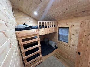 A compact wooden cabin room with bunk beds, a small window, and a door. - The Moose Cabin, cozy cabin right on the Atv and snowmobile trail access road.  (Baileyville)