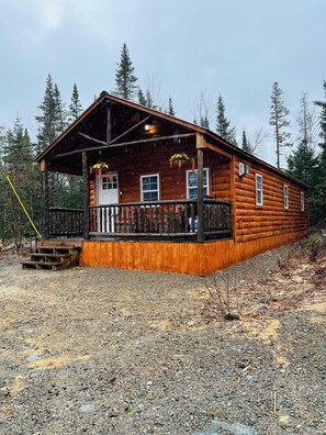A log cabin with a porch, multiple windows, and a number '2184' on the door. - The Moose Cabin, cozy cabin right on the Atv and snowmobile trail access road.  (Baileyville)