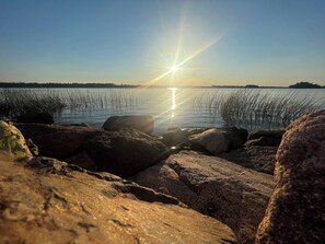 A rocky shoreline with a calm lake and a clear sky. - The Moose Cabin, cozy cabin right on the Atv and snowmobile trail access road.  (Baileyville)