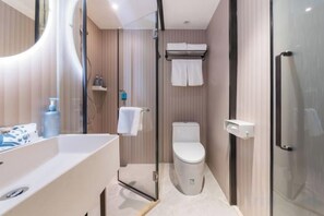 A modern bathroom with a glass shower enclosure, a toilet, and a sink with a mirror. - HanTing Hotel (Shenzhen Xili Subway Station) (Shenzhen)