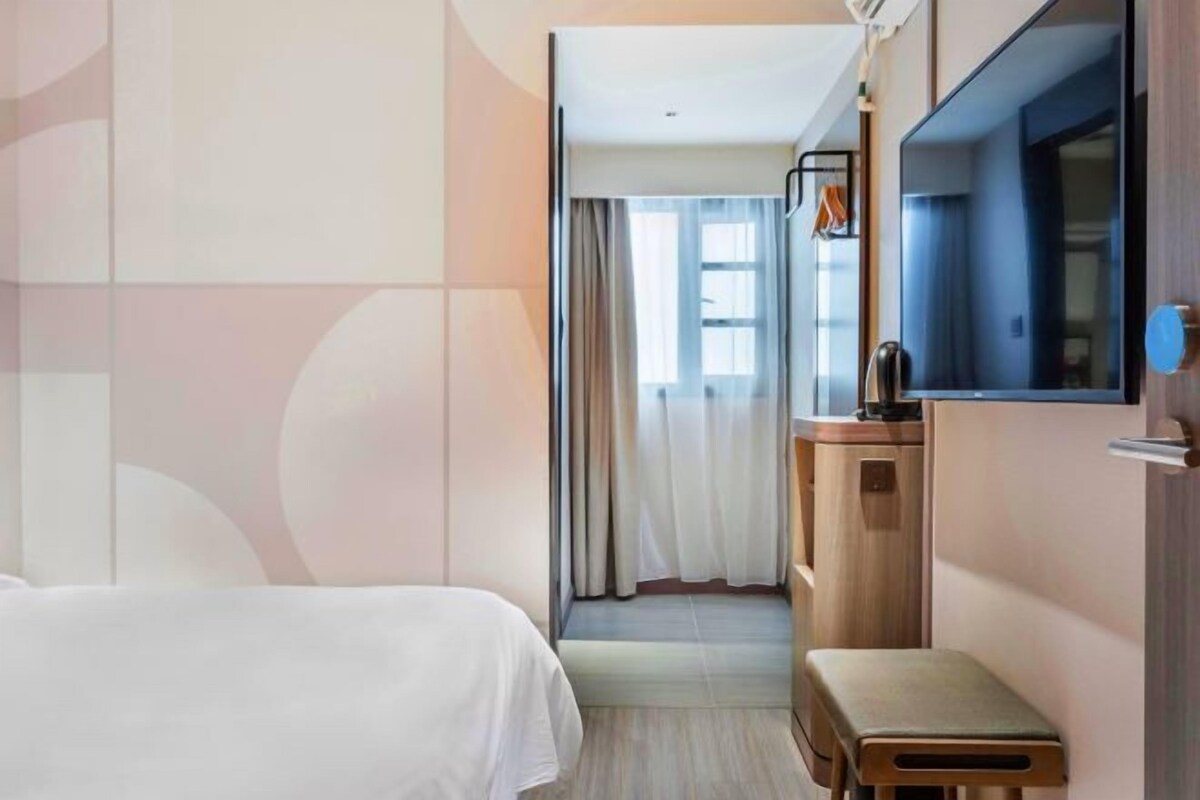 Una habitación de hotel con cama, una mesita, un espejo y una ventana con cortinas.