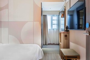 Una habitación de hotel con cama, una mesita, un espejo y una ventana con cortinas.