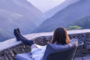 Una persona sentada en una silla con cojín, contemplando un paisaje montañoso.