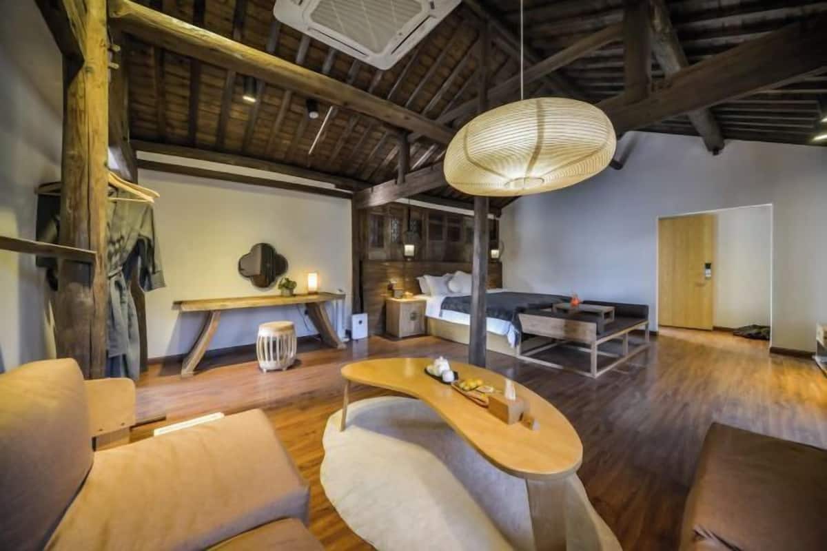 A modern interior with a wooden ceiling, a curved wooden table, and a sofa.