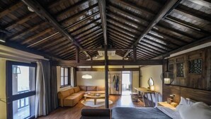 A spacious room with a high ceiling, wooden beams, a large bed, a sofa, a dining area, and a view through a large window. - Cloud Retreat Songyang (Songyang)