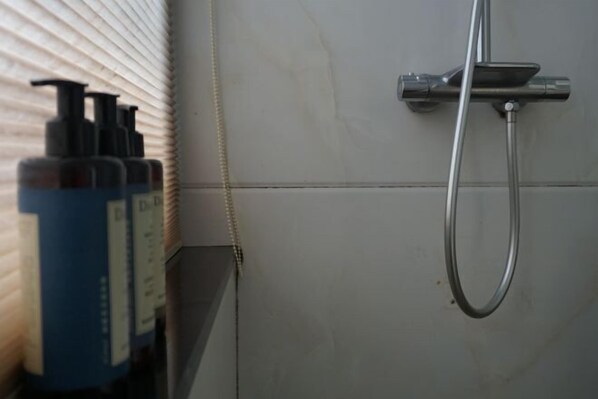 A bathroom with a shower, a towel rack, and a bottle of shampoo. - Cloud Retreat Songyang (Songyang)