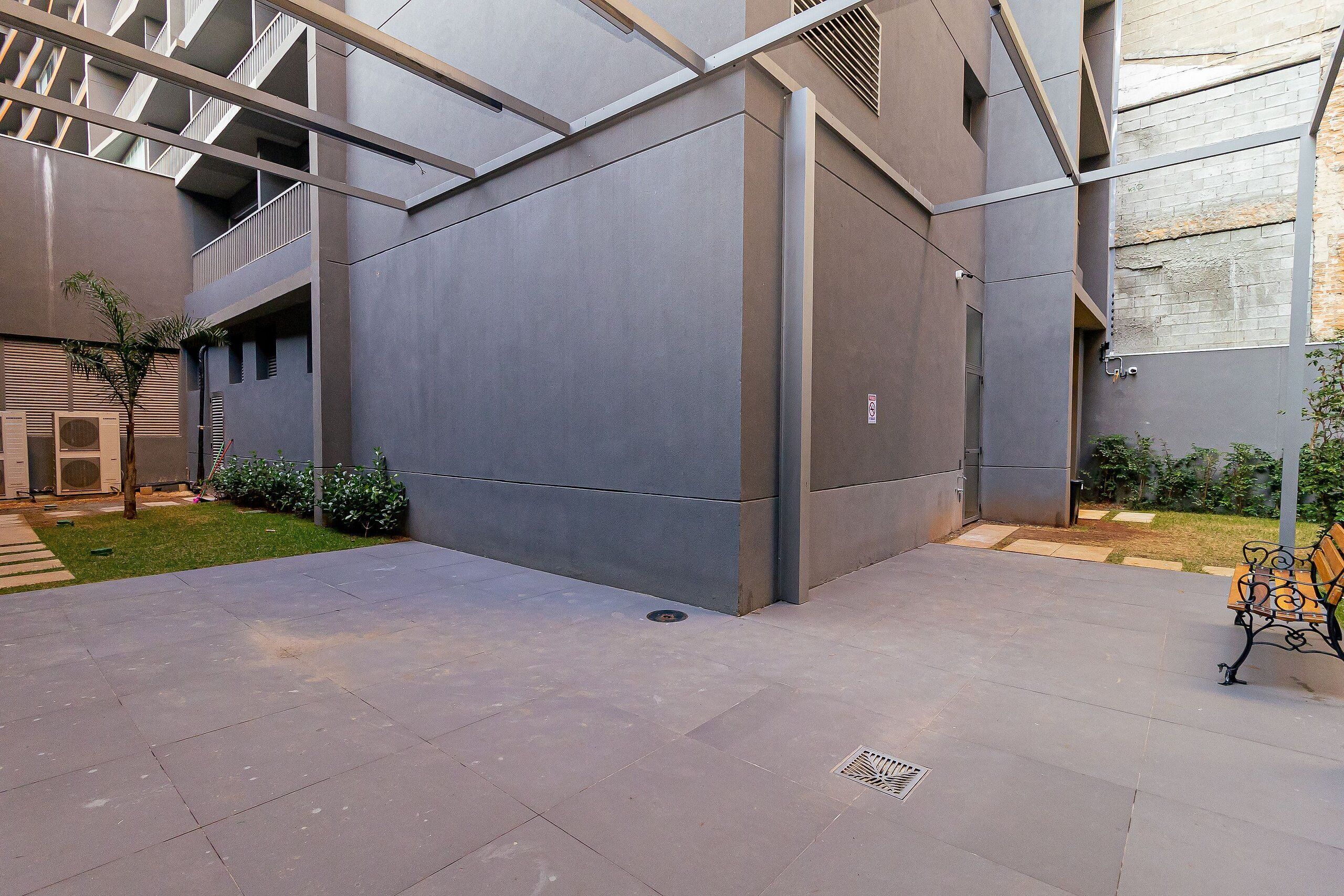 A modern building with a flat roof, large windows, and a courtyard with a bench.