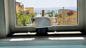 Ein Fenster mit Meerblick, ein Glas Wasser und ein Handtuch auf der Fensterbank.