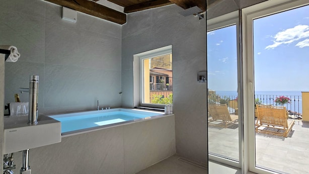 Ein Badezimmer mit einer Badewanne, einem Fenster und Blick aufs Meer.