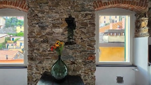 Ein Zimmer mit einer Steinsäule und zwei Fenstern mit Blick auf eine Stadtlandschaft.