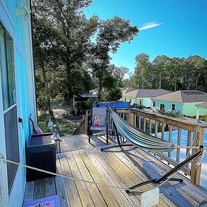 A wooden deck with a hammock, a small table, and a chair.