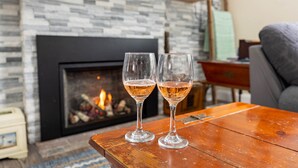 Deux coupes de champagne sur une table en bois, devant une cheminée dont le mur est en pierre.