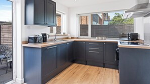 Een moderne keuken met donkere kasten, een houten aanrecht en een groot raam dat voor natuurlijk licht zorgt.