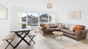 Een moderne woonkamer met een bank, salontafel en eettafel.