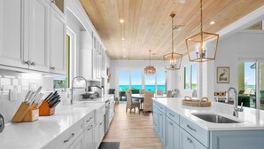 A modern kitchen with white cabinets, a wooden ceiling, and a view of the ocean. - Yumey Sands Villa, Heated Pool & Unbelievable Year-Round Calm Beach (Moore Hill)