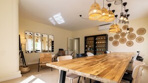 Un vaste espace dédié à la salle à manger, avec une grande table en bois, des chaises modernes et une collection de paniers tressés.