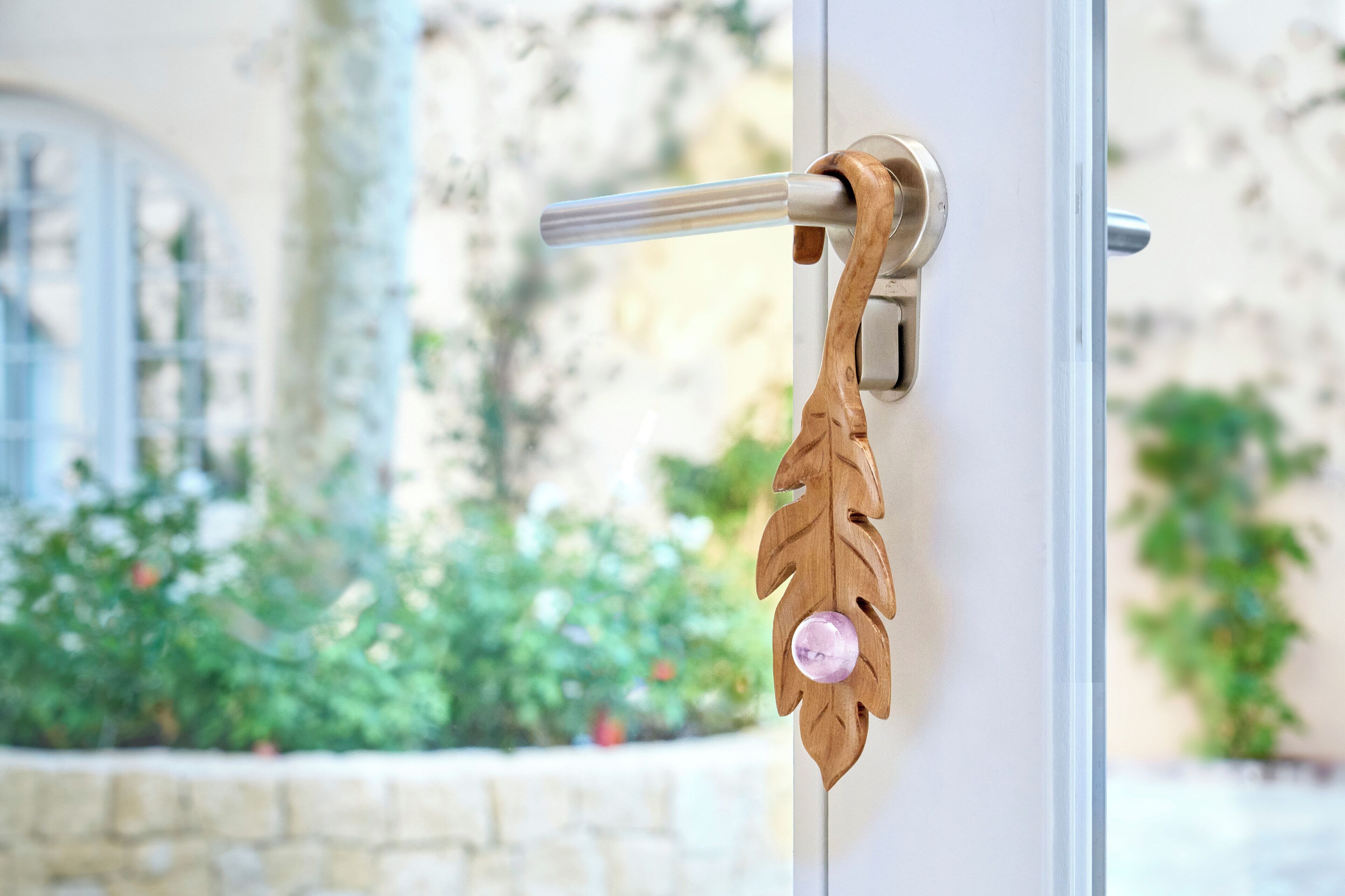 A door handle with a wooden leaf-shaped design and a pink gem.