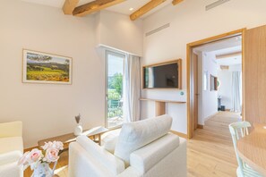 A modern living room with a sofa, a TV mounted on the wall, and a painting on the wall. - Auberge La Coste (Le Puy-Sainte-Reparade)