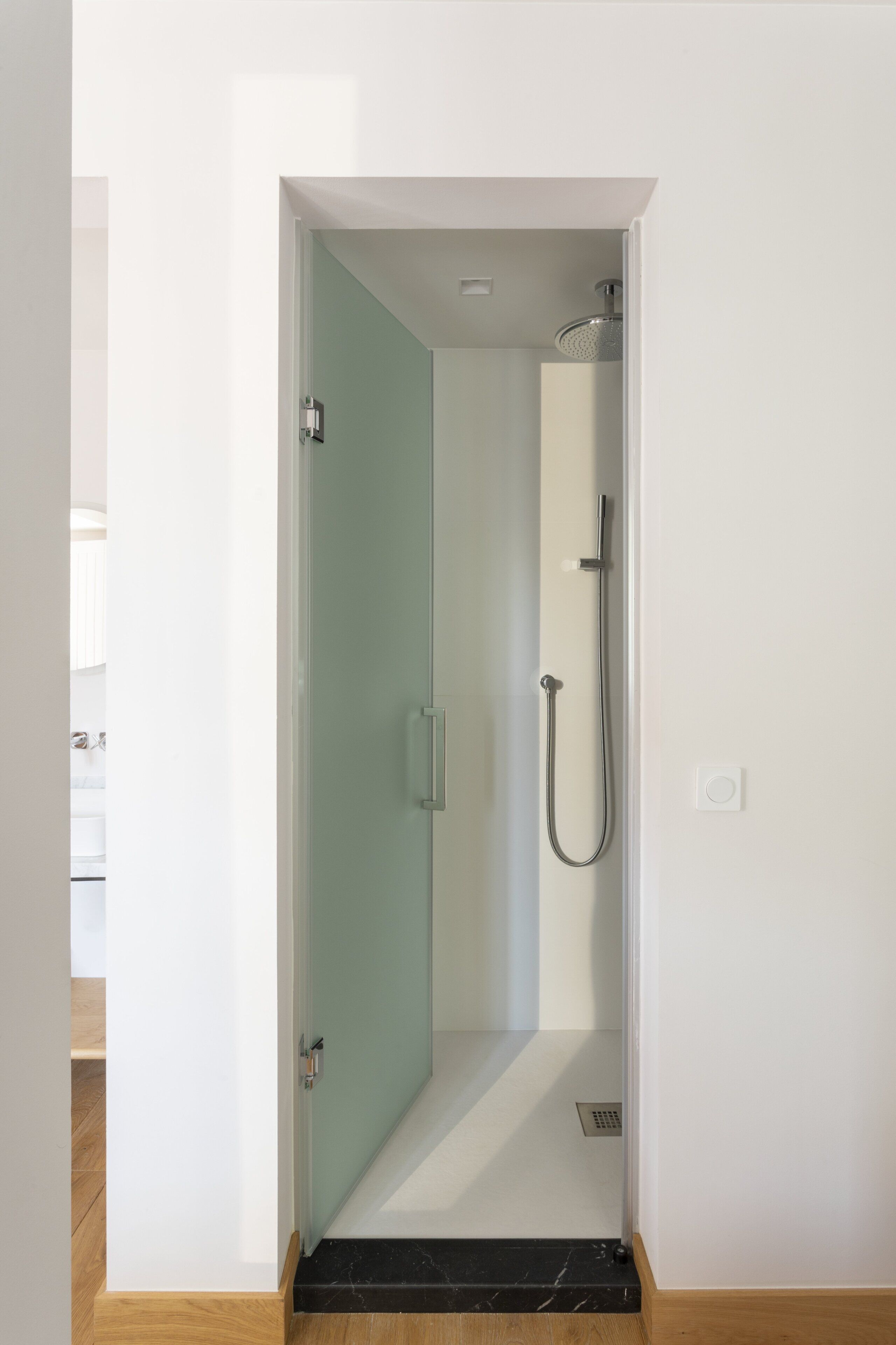 Une petite salle de bain moderne avec une porte en verre, une douche et des toilettes.