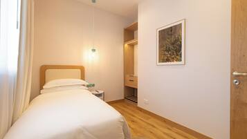 A bedroom with a bed, bedside table, lamp, and a framed picture on the wall.