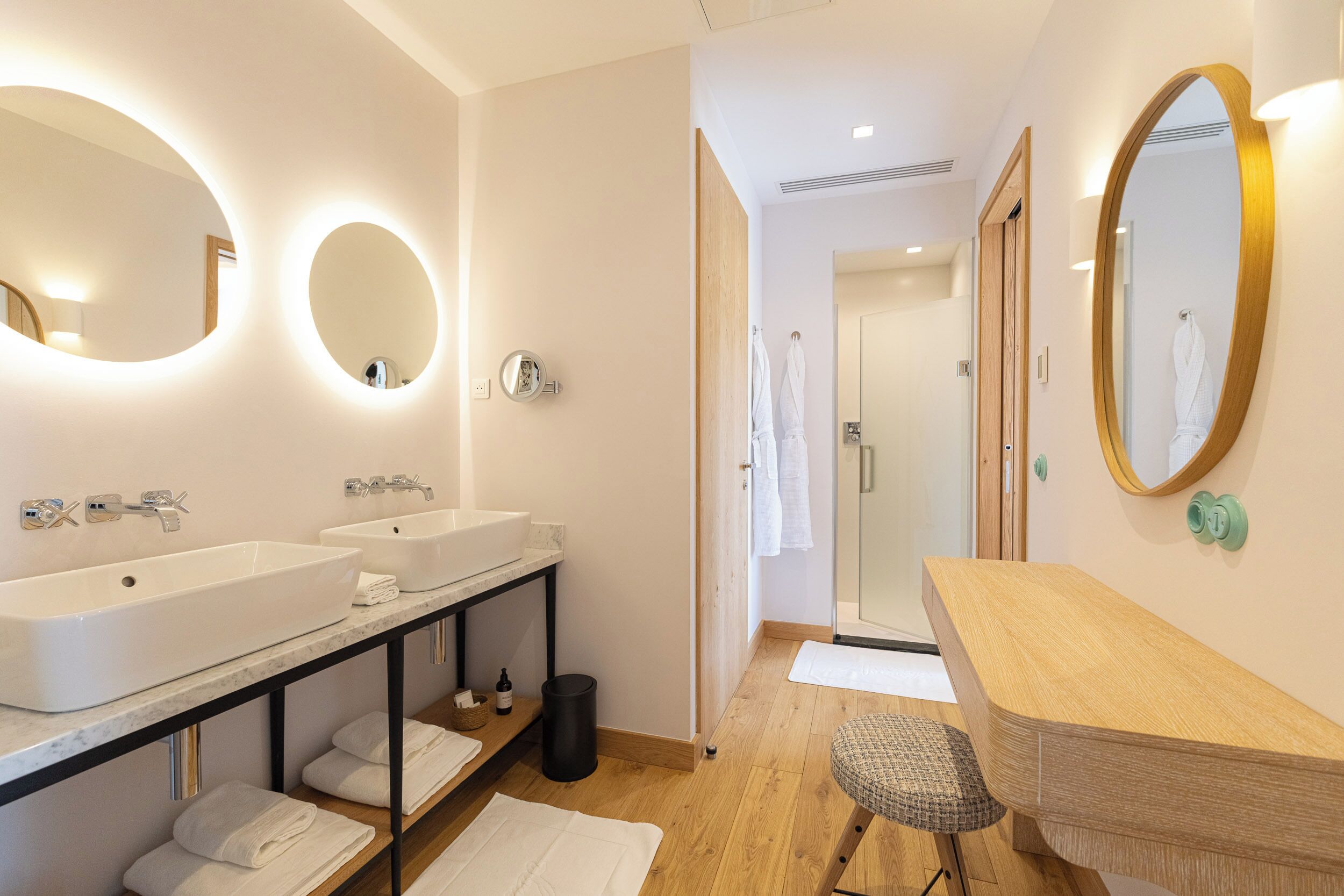 Un baño moderno con dos lavabos, tocador y espejo.