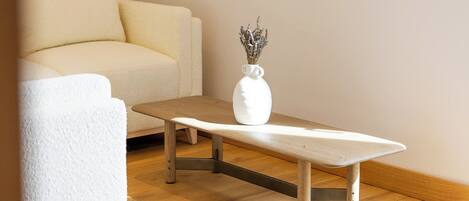 Une pièce avec un canapé blanc, une table basse en bois et un tableau représentant un paysage, accroché au mur.