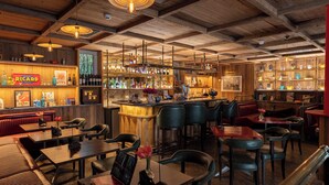A bar area with wooden beams, bar stools, and a variety of bottles and glasses. - Auberge La Coste (Le Puy-Sainte-Reparade)