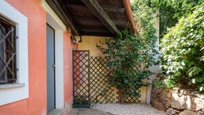 Un patio con un sendero de piedra, una puerta de madera, una valla de celosía y un muro de piedra.