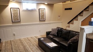 A living room with a leather sofa, ottoman, and decorative wall art. - 1-bedroom apartment in Albany with WiFi, AC (Menands)