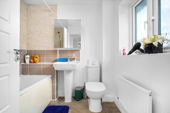 Un baño moderno con bañera, lavamanos, inodoro y ventana con vistas.