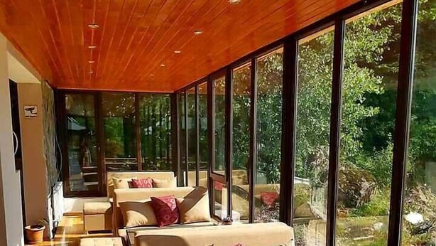 A modern interior with wooden ceiling, large windows, and a series of sofas and tables. - Hotel Mountain Mestia (Mestia)