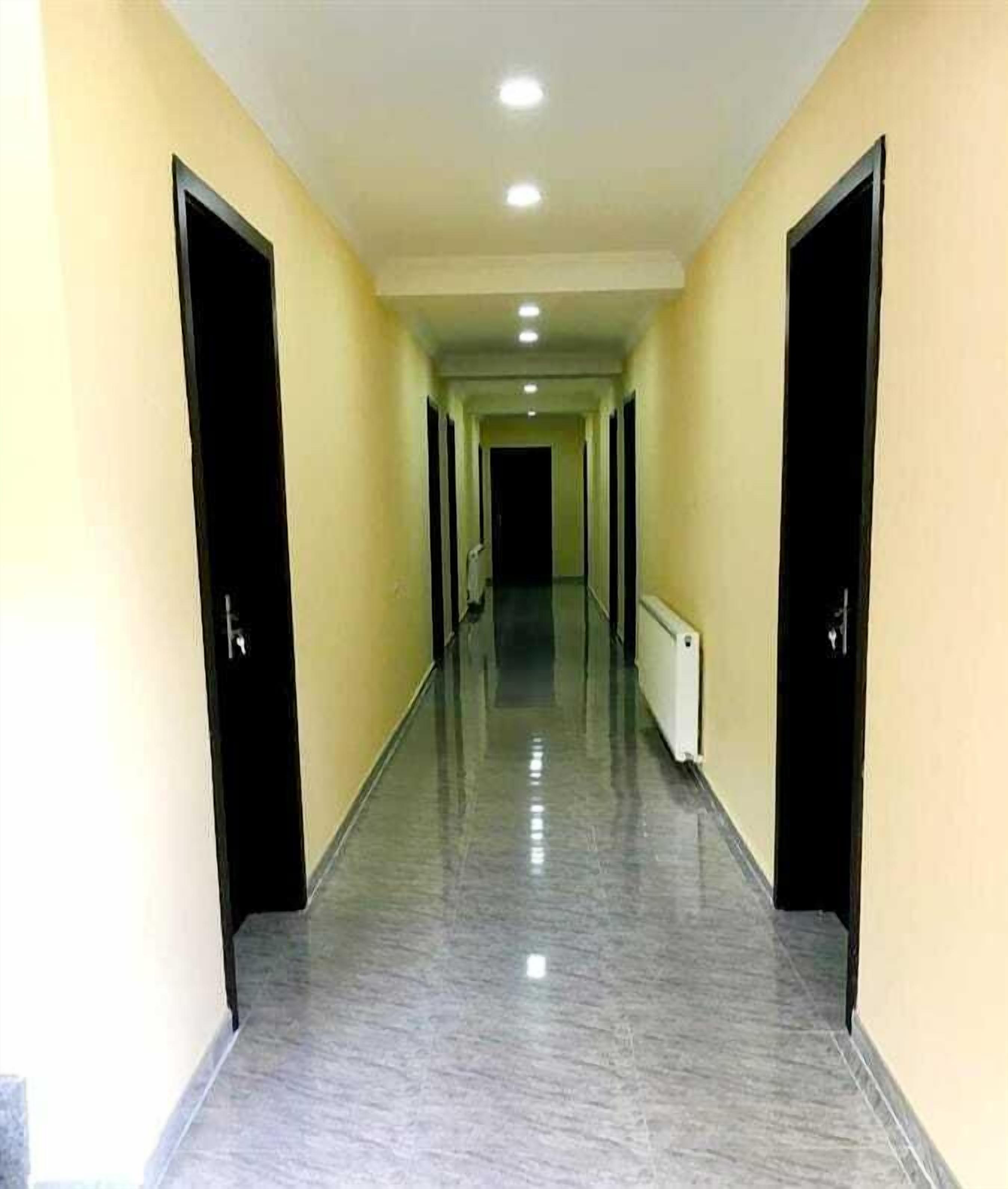 A long, narrow hallway with doors on both sides and a radiator on the right wall.