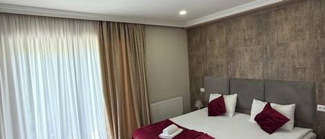 A hotel room with a large bed, a bench, a TV, a patterned rug, and a wooden headboard.