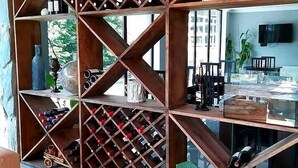 A wine rack with bottles, a television, and a dining area with chairs and a table. - Hotel Mountain Mestia (Mestia)