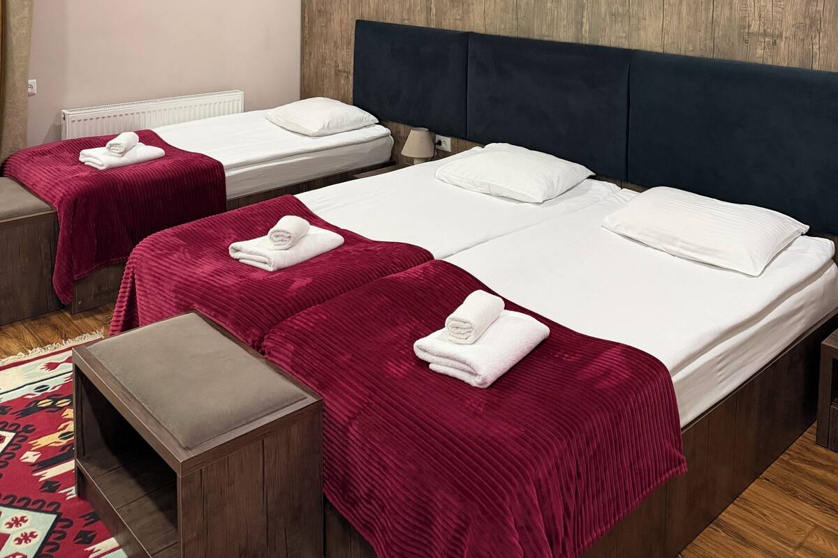 A hotel room with two beds, a wooden headboard, and a red carpet.