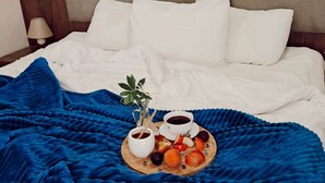 A neatly made bed with white linens, a blue blanket, and a breakfast tray with fruits, a cup of coffee, and a small plant. - Hotel Mountain Mestia (Mestia)
