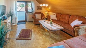 A cozy living room with a wooden ceiling, a sofa, a coffee table, and a TV.