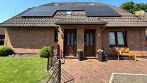 A two-story house with a brick facade, a front porch, and solar panels on the roof.