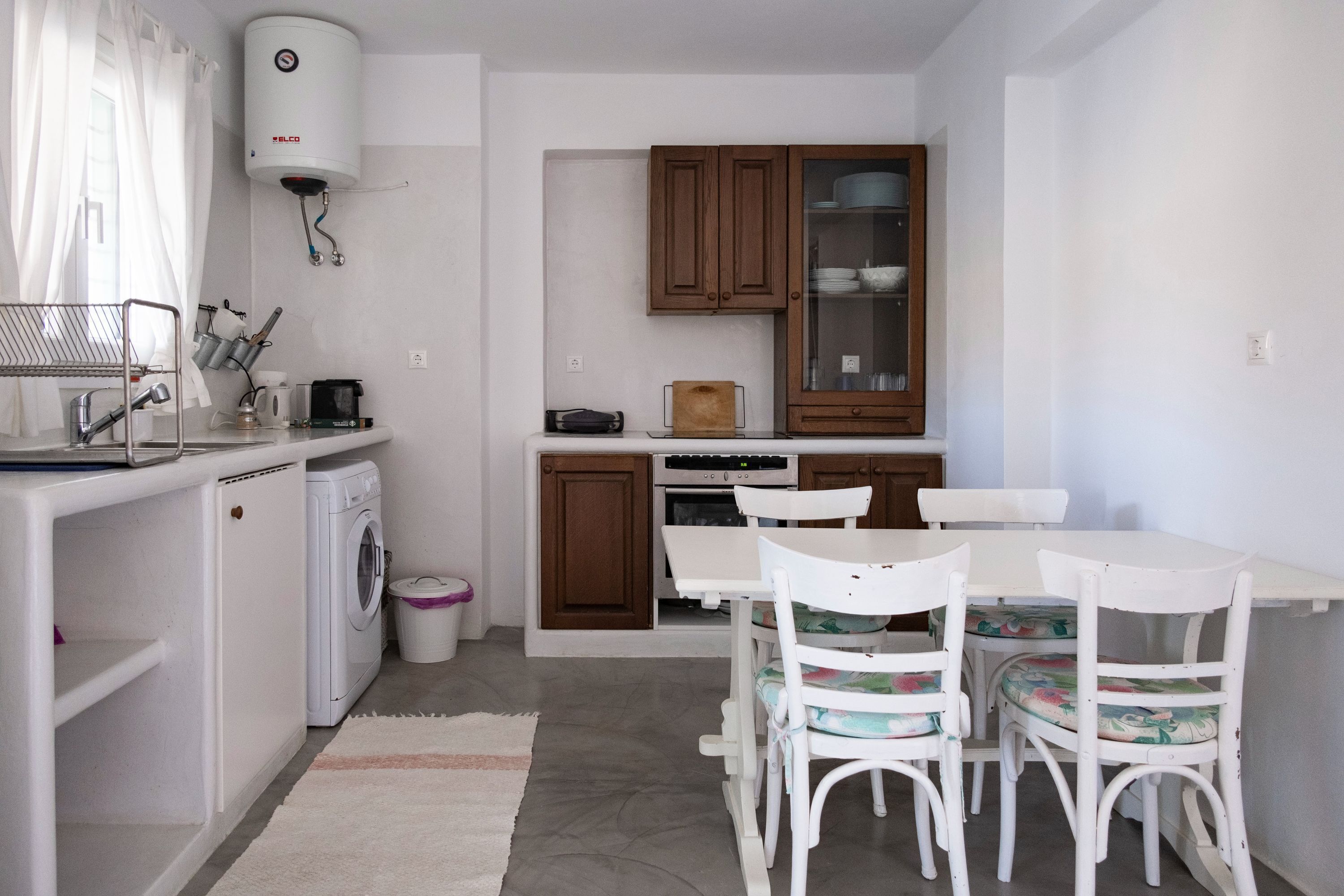A compact kitchen with a washing machine, a stove, and wooden cabinets.