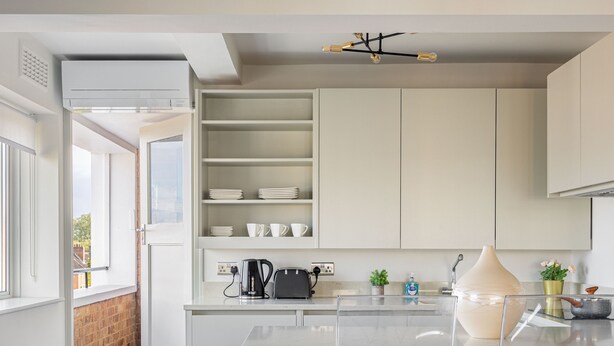 A modern kitchen with white cabinets, a glass island, and a view to the outside. - Lux Regents Park 2 bed 2 Bath Flat With AC (London)