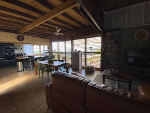A spacious living area with a wooden ceiling, a dining table, and a sofa. - Sea Lodge : Maison Avec Vue Imprenable - Votre Refuge de Vacances Idéal (Sainte-Anne)