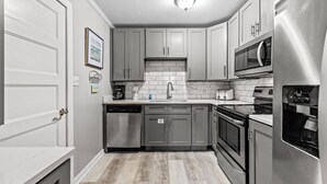 Una cuina moderna amb armaris grisos, un rentaplats, un microones i un frigorífic.