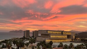 A modern hotel with a unique architectural design, featuring a prominent vertical structure and a waterfront view. - Spend your Christmas week in Cabo at Villa La Valencia (San José del Cabo)