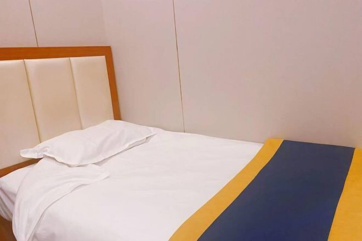 A bed with a wooden headboard and white bedding.