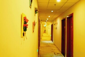 A corridor with doors on the right, a carpeted floor, and a wall-mounted decoration on the left. - Oriental Hotel (Beijing)